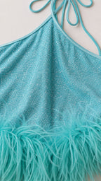 Close up of glitter fabric and turquoise feather hem