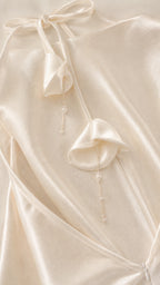 Close-up detail of back tie straps with floral and bead drops on white satin