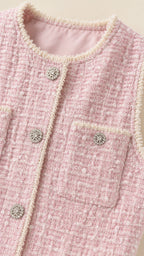 Close-up detail of pearl trim and jeweled buttons on pink tweed dress