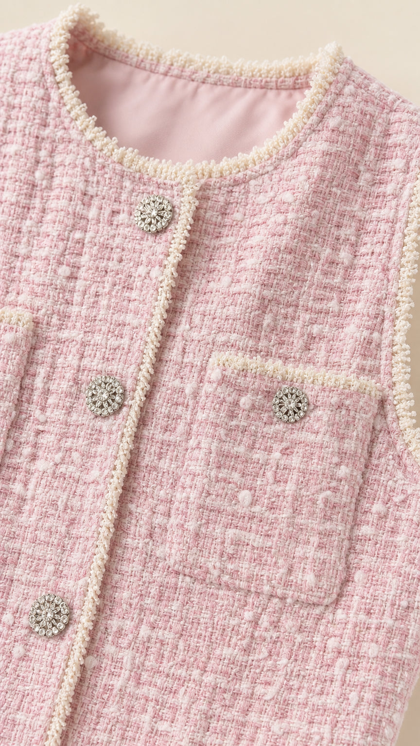 Close-up detail of pearl trim and jeweled buttons on pink tweed dress