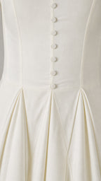 Close-up detail of front buttons and pleated waist on white dress