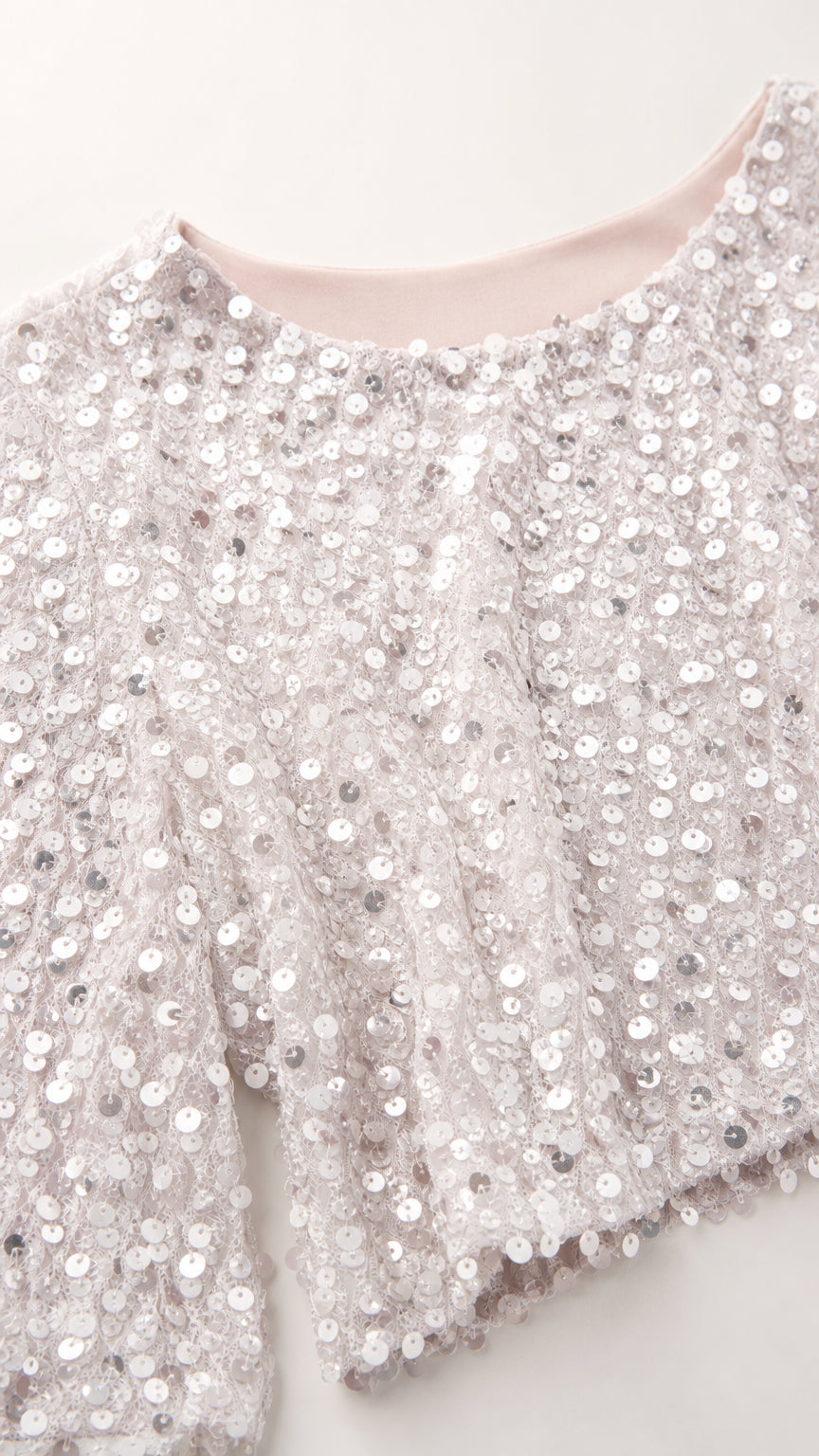 Close-up detail of silver sequin texture and crew neckline