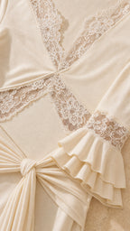 Close-up of lace neckline and ruffled bell cuffs on ivory dress