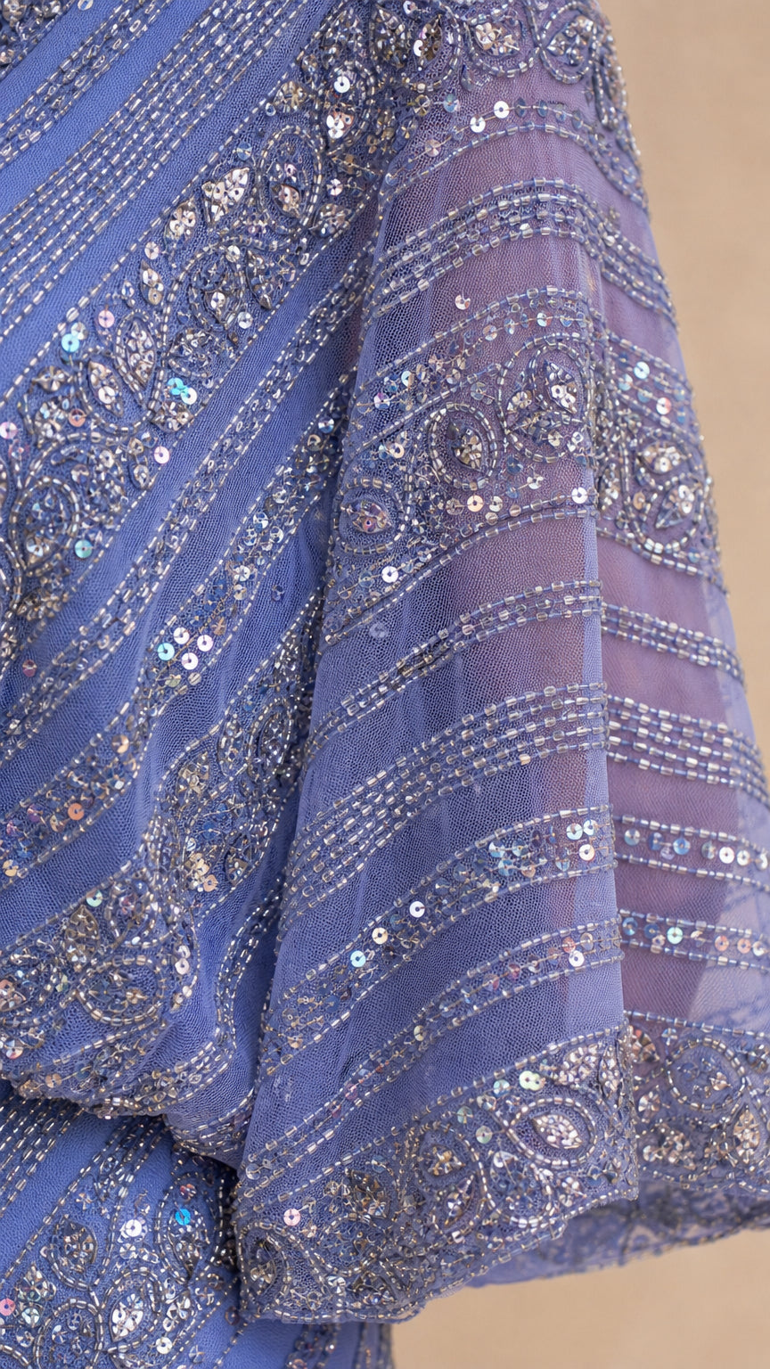 Close-up detail of geometric bead and sequin embellishments on blue mesh fabric