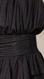 Close-up detail of smocked waist and textured fabric on black romper