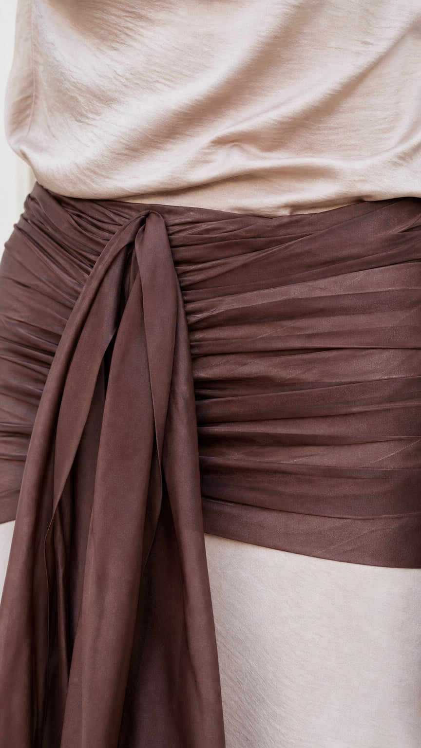 Close-up detail of ruched brown waist sash and fabric texture