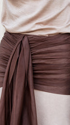 Close-up detail of ruched brown waist sash and fabric texture