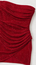 Close-up detail of red glitter ruched fabric and asymmetrical hem