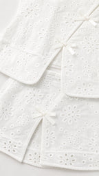 Close-up of white eyelet fabric and bow details