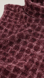Close-up of fabric texture and mock neck detail in burgundy