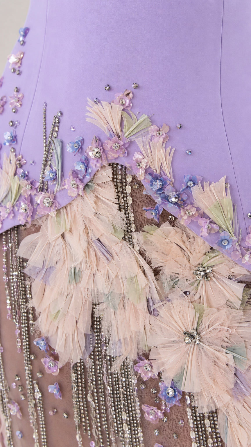 Close-up detail of floral appliques, feathers, and beading on gown