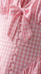 Close up of pink gingham dress bodice with bow and buttons