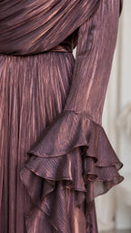 Close-up detail of the metallic pleated fabric and multi-layered ruffle cuffs