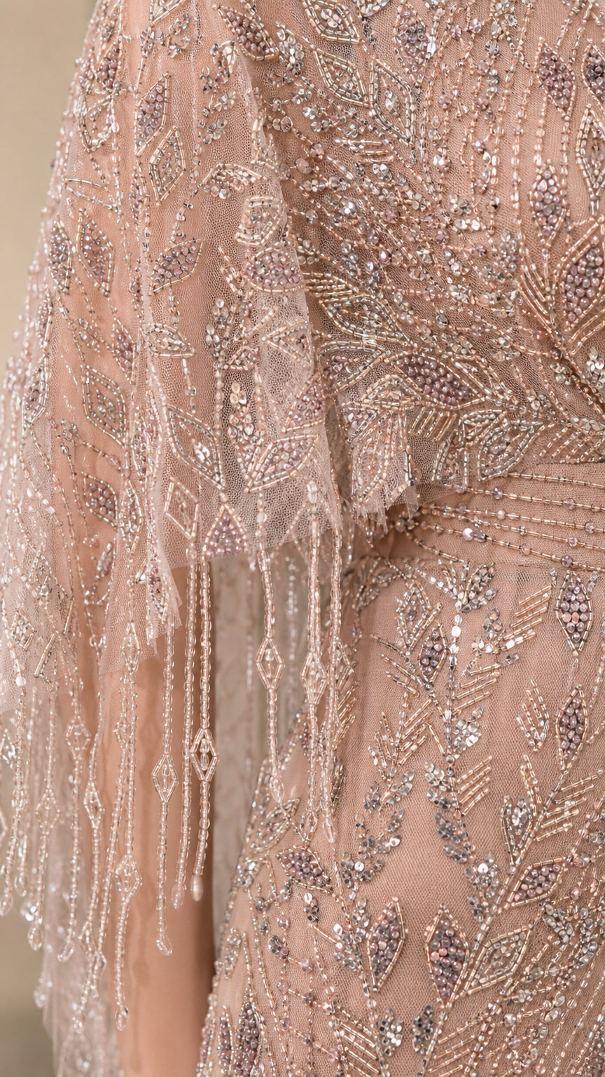 Close-up detail of sequin and bead pattern with fringe cape sleeve
