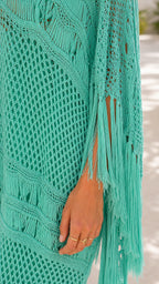 Close-up detail of teal crochet knit and fringe texture