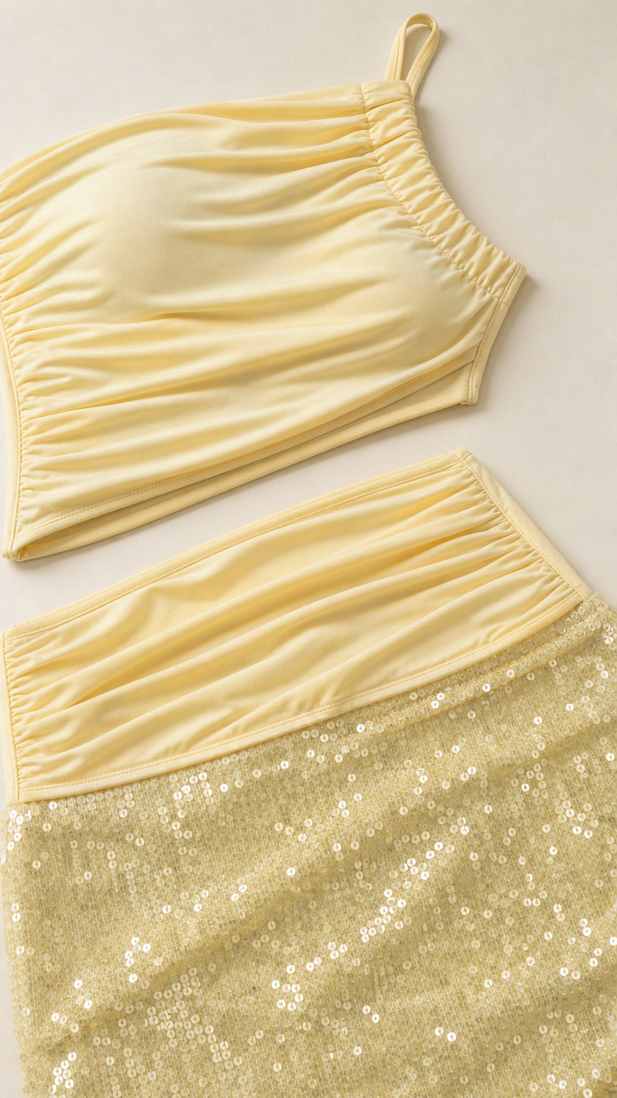 Detailed flat lay of yellow one-shoulder top and sequin skirt waistband