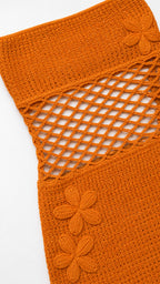 Close-up of orange crochet texture, net cutout, and floral appliques