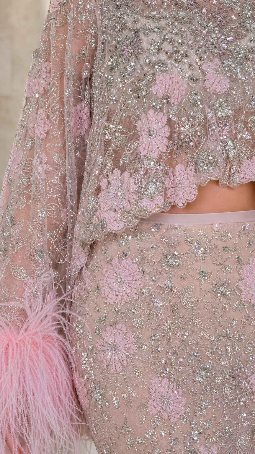 Close-up detail of embroidery, beading, and feather cuffs on pink set