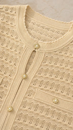 Close-up detail of beige knit top featuring pearl buttons and textured pattern