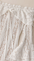 Close-up detail of the white lace fabric, neckline, and bow tie accents