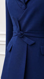 Close-up detail of blazer lapel, buttons, and waist tie in royal blue
