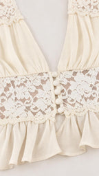 Close-up of lace trim and button details on cream crop top