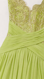 Close-up detail of the embroidered V-neck bodice and wrapped pleated waist