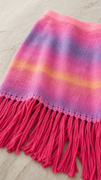 Close-up detail of the pink ombre striped knit fabric and fringe hem