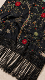 Close-up detail of embroidery and fringe hem on black dress