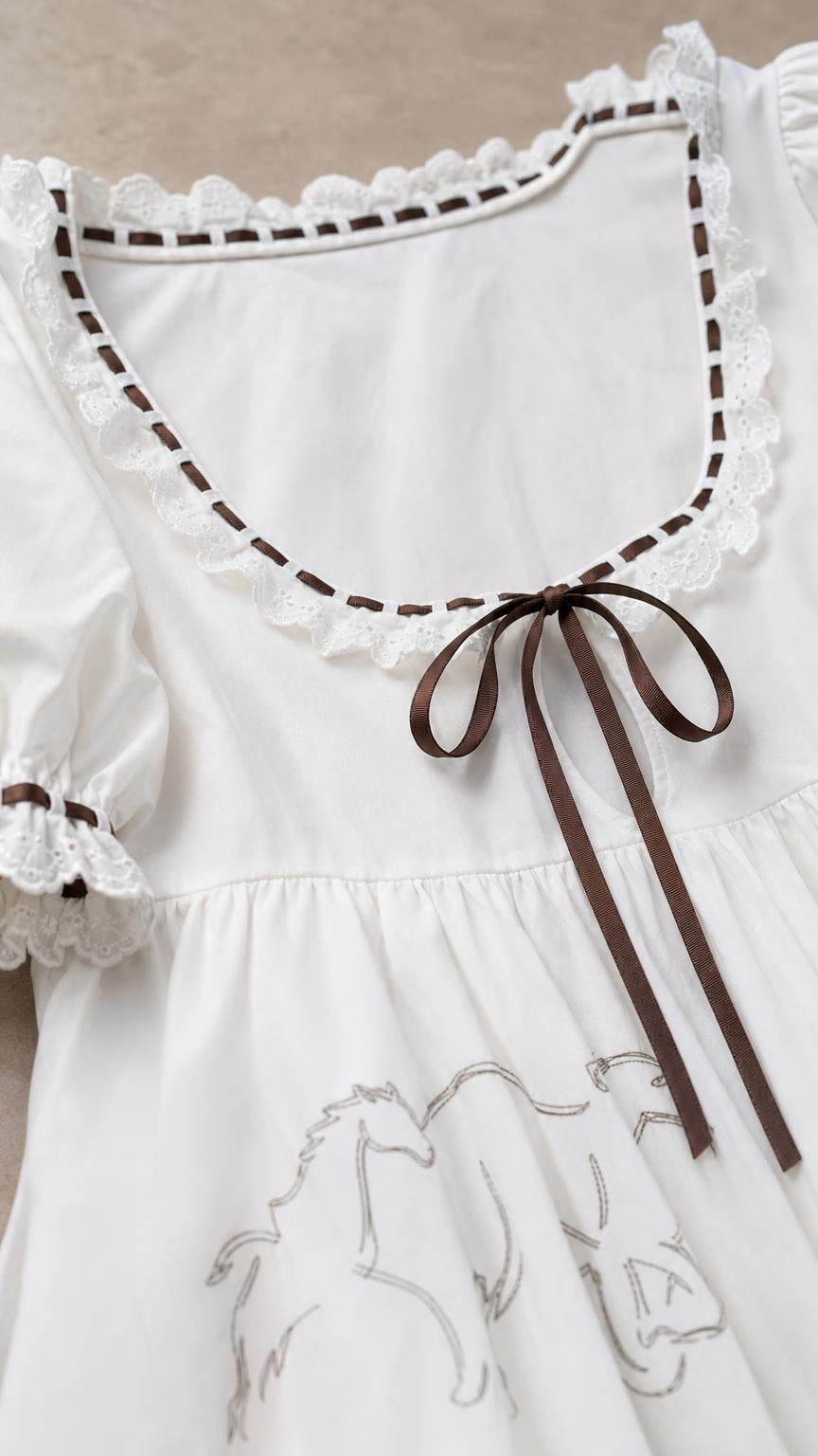 Close-up detail of scoop neckline, lace trim, and ribbon bow