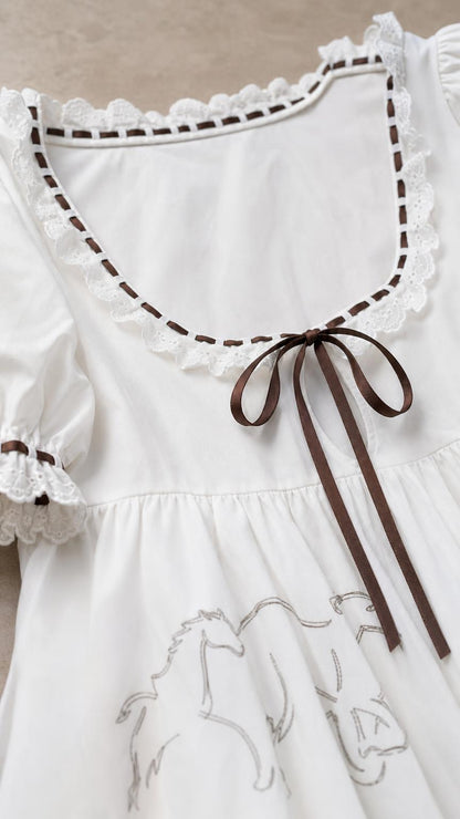 Close-up detail of scoop neckline, lace trim, and ribbon bow