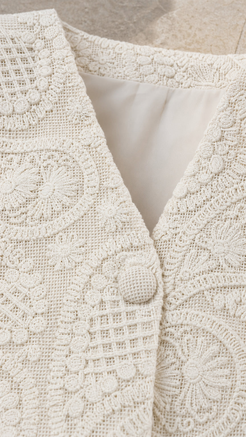 Close-up detail of cream textured fabric and button
