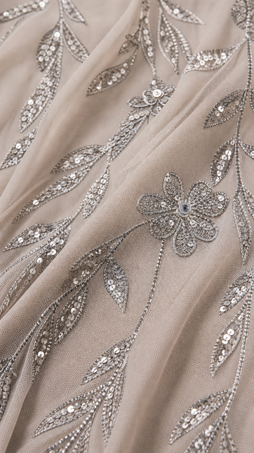 Close-up fabric detail showing intricate sequin vine and flower embroidery on mesh