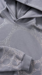 Close-up detail of grey hoodie hood and rhinestone graphic fabric