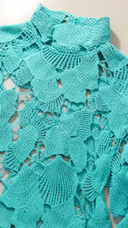 Close-up detail of turquoise floral crochet fabric and high neckline