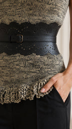 Close-up detail of the wide decorative belt and textured hem with pocket