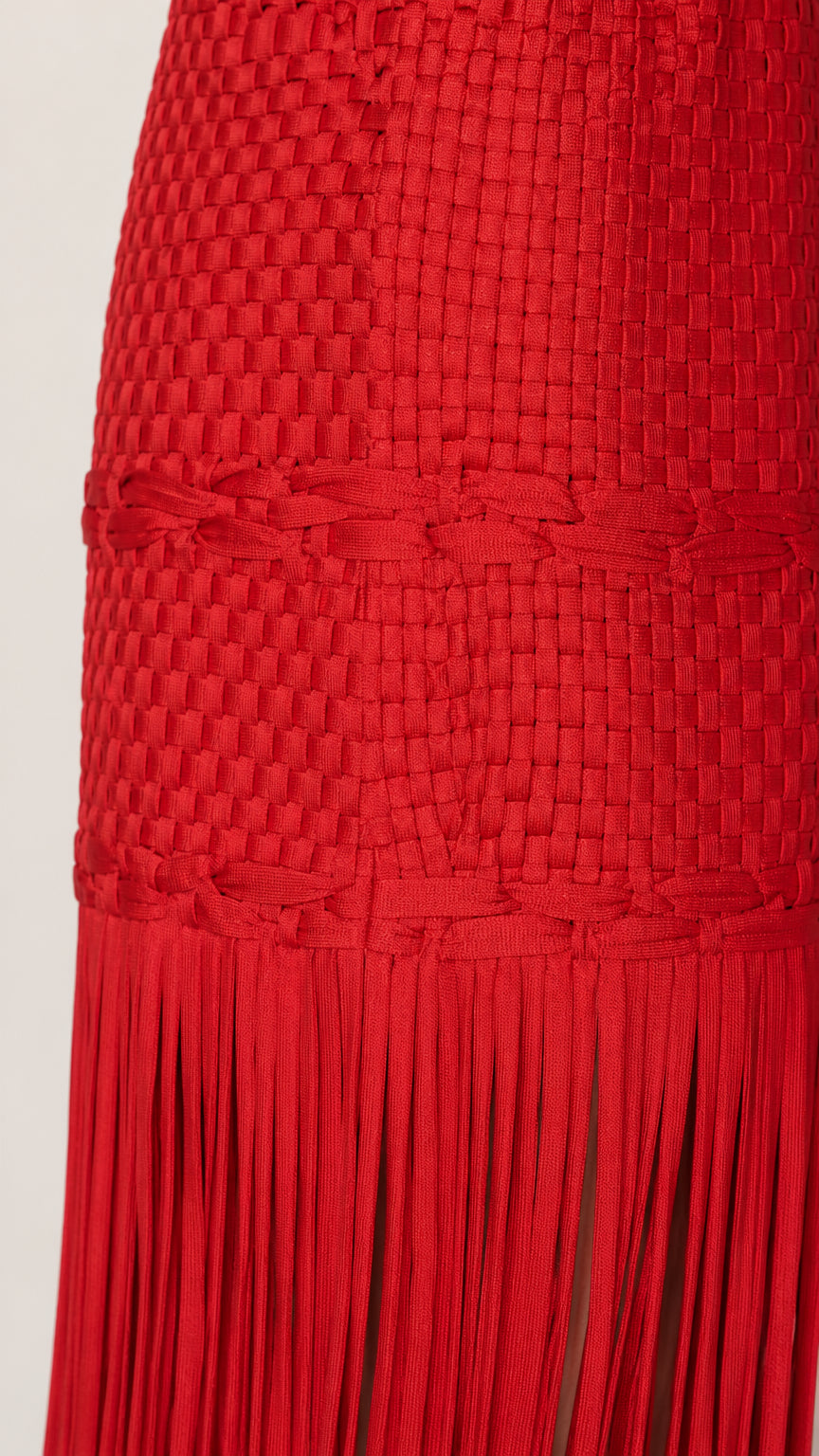 Close-up detail of the woven texture and fringe hem on the red dress