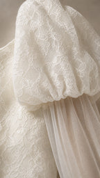 Close-up detail of lace puff sleeve and sheer cape