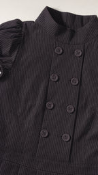 Close up of mock neck and double breasted buttons on black dress
