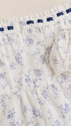 Close up of bodice details and ribbon trim on white floral dress