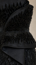 Close-up detail of black textured beadwork and satin peplum waist