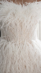 Close up of intricate beadwork and feather texture on white dress