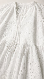 Close-up detail of white eyelet embroidery and tie neckline