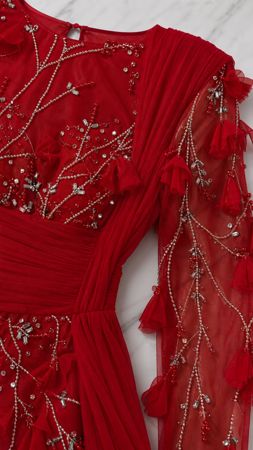 Close up of bodice beadwork and sheer sleeves on the red gown
