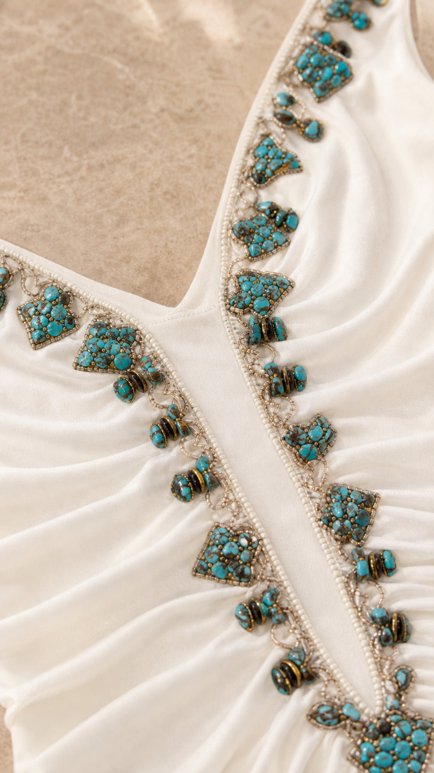 Close-up detail of turquoise bead embellishments on white dress neckline