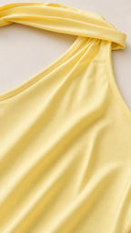 Close-up of the smooth yellow satin fabric and one-shoulder halter neckline