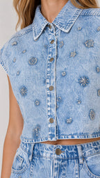 Close-up detail of rhinestone floral pattern on light blue denim button-up vest