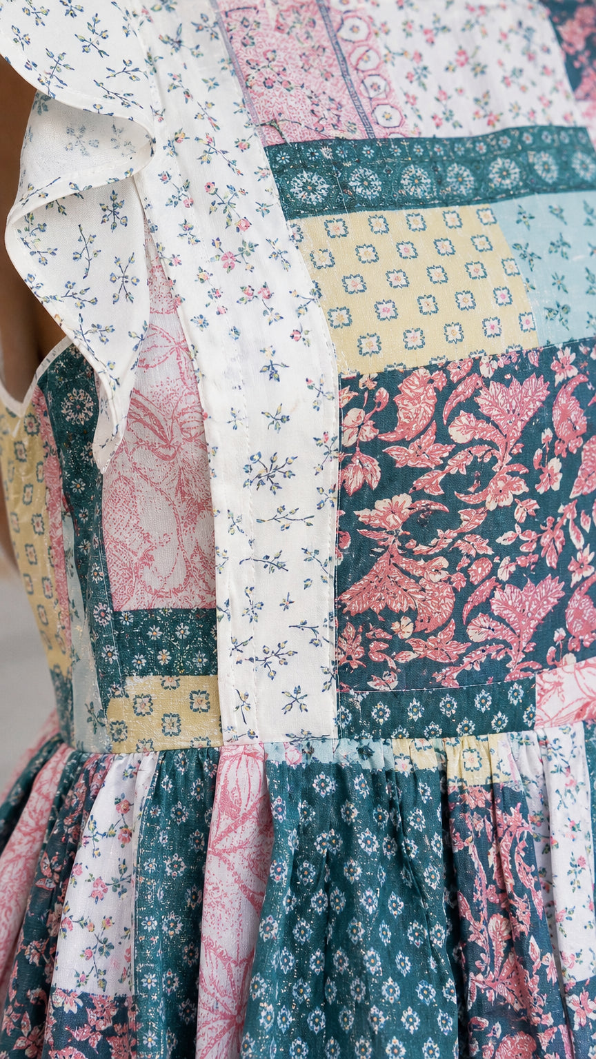 Close-up detail of patchwork fabric and ruffle sleeve