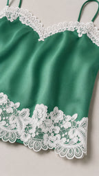 Close-up of green satin fabric and white lace trim detail