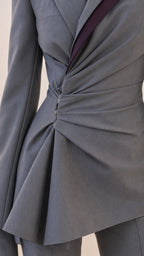 Close-up detail of the asymmetric ruched waist and contrasting lapel